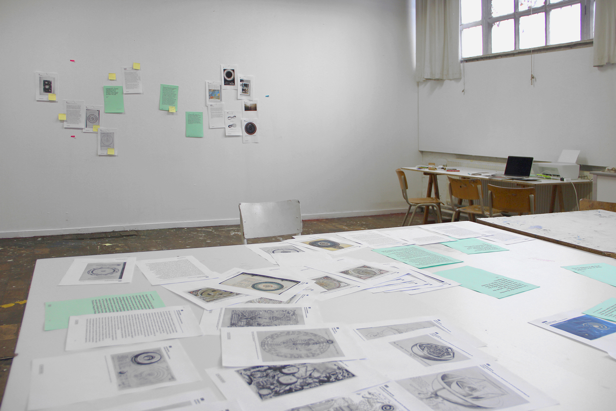 Photographie d'un workshop: feuilles disposées sur une table et sur un mur